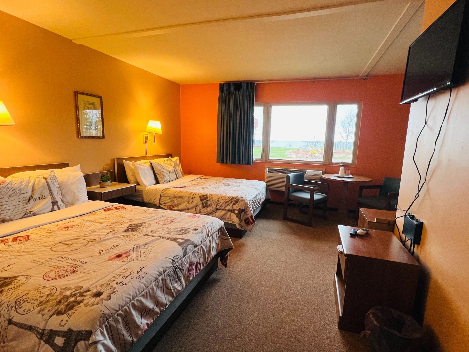 A hotel room with two beds , a table and a television.