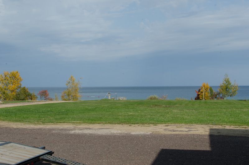 A view of the ocean from a patio with a table and chairs.