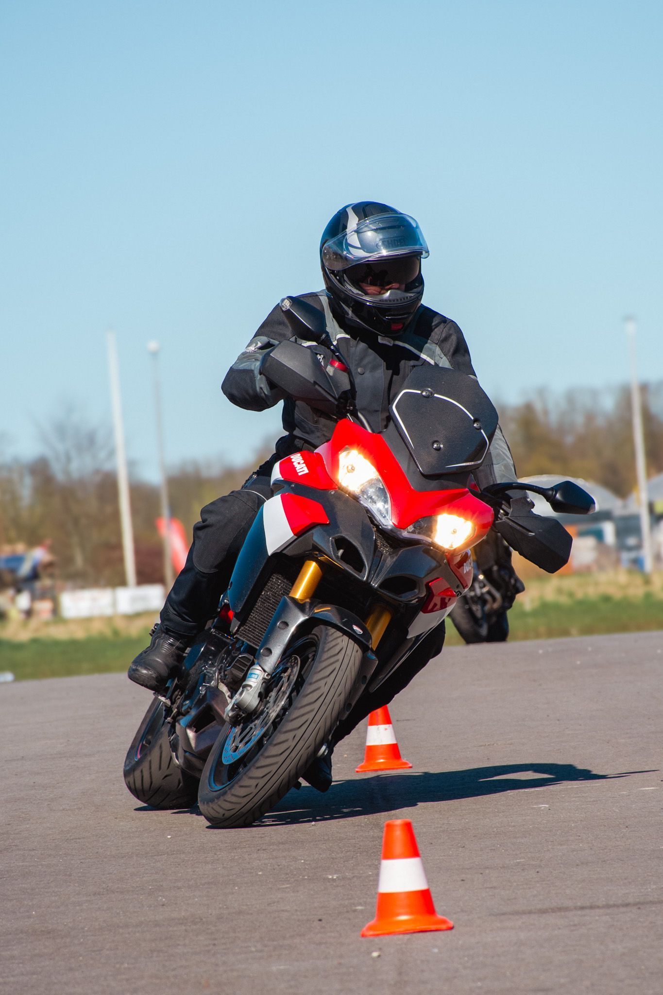 Een man rijdt op een motorfiets op een weg naast kegels.