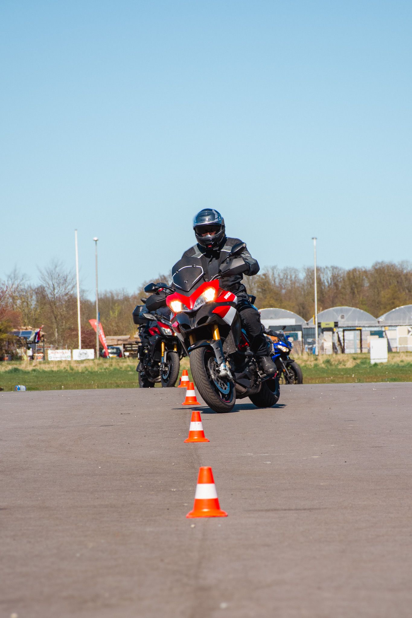 Een man rijdt op een motorfiets over een weg naast kegels.