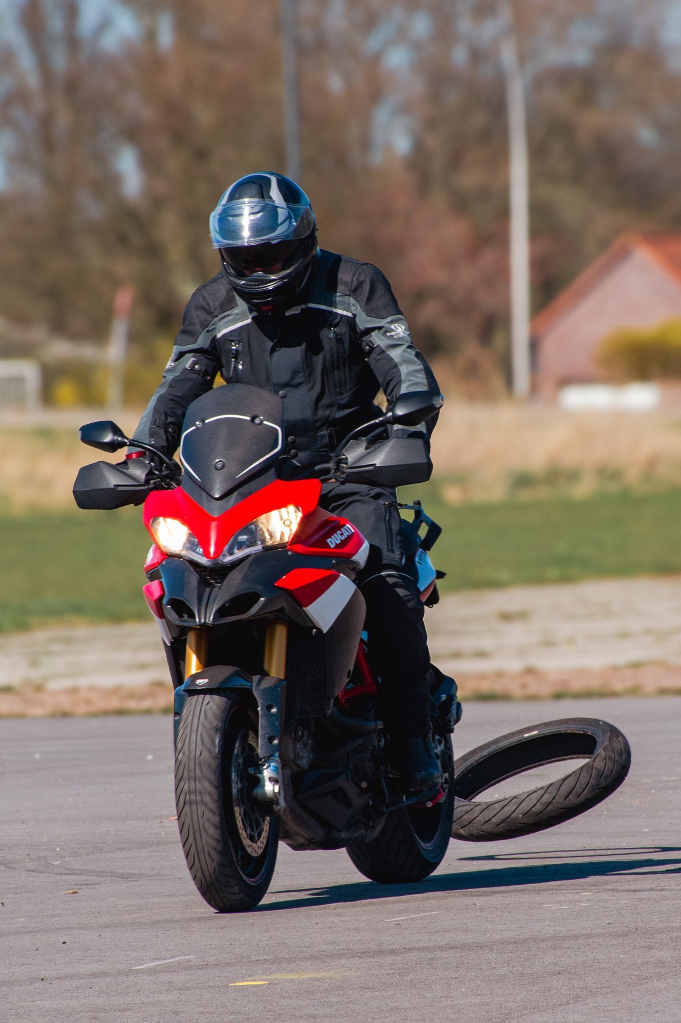 Een man rijdt op een motorfiets, met een lekke band op de grond.