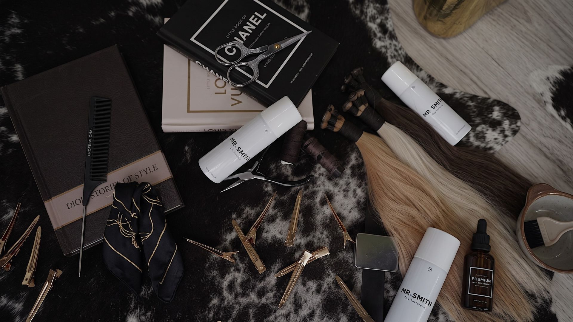 Flat lay of luxury beauty products and makeup on a marble surface, with a magazine and candles
