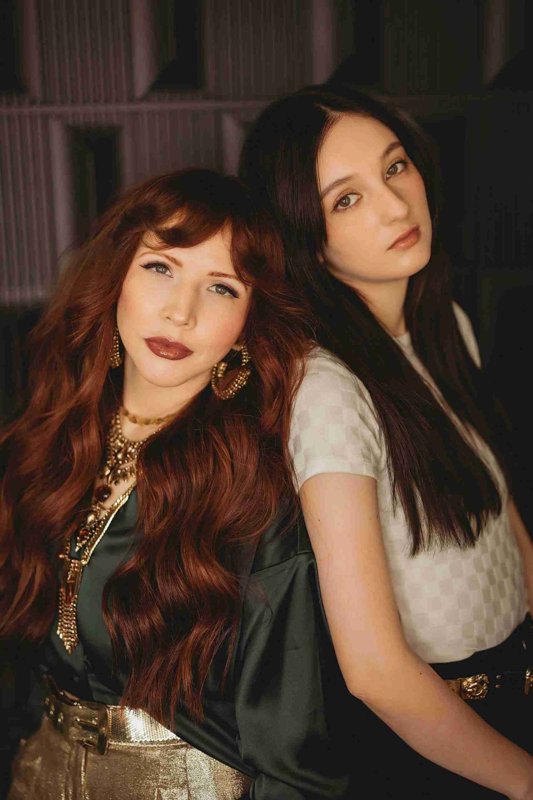Two women with long red hair are posing for a picture.