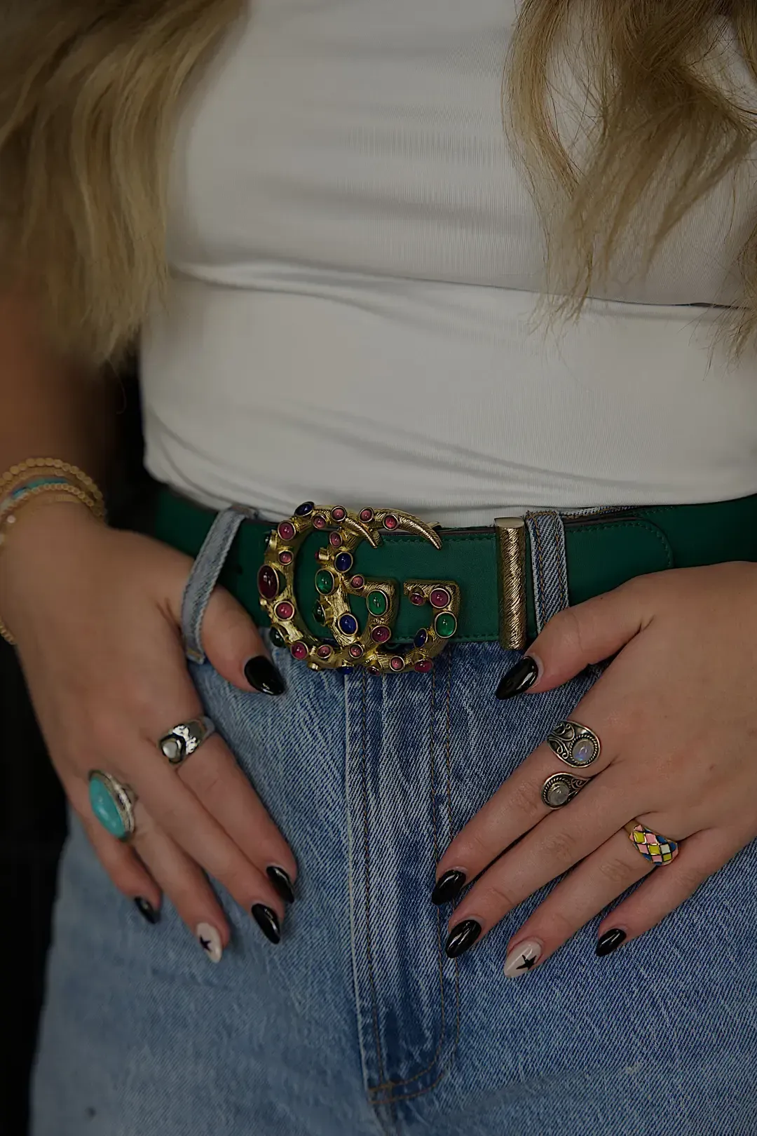 Statement Gucci belt styled with colorful rings and detailed manicure