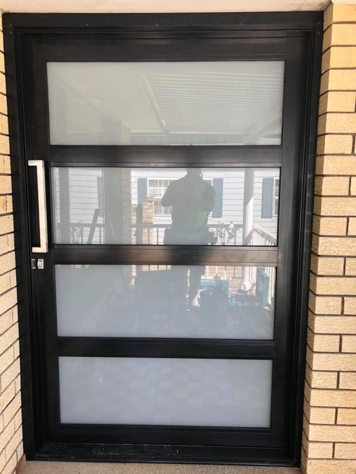 A Black Door with A White Handle Is on A Brick Wall — Distinctive Glass & Aluminium in Shellharbour, NSW