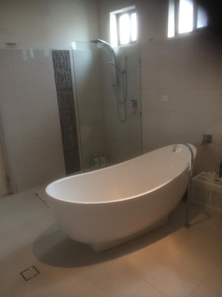 A White Bathtub Is Sitting in A Bathroom Next to A Shower — Distinctive Glass & Aluminium in Port Kembla, NSW