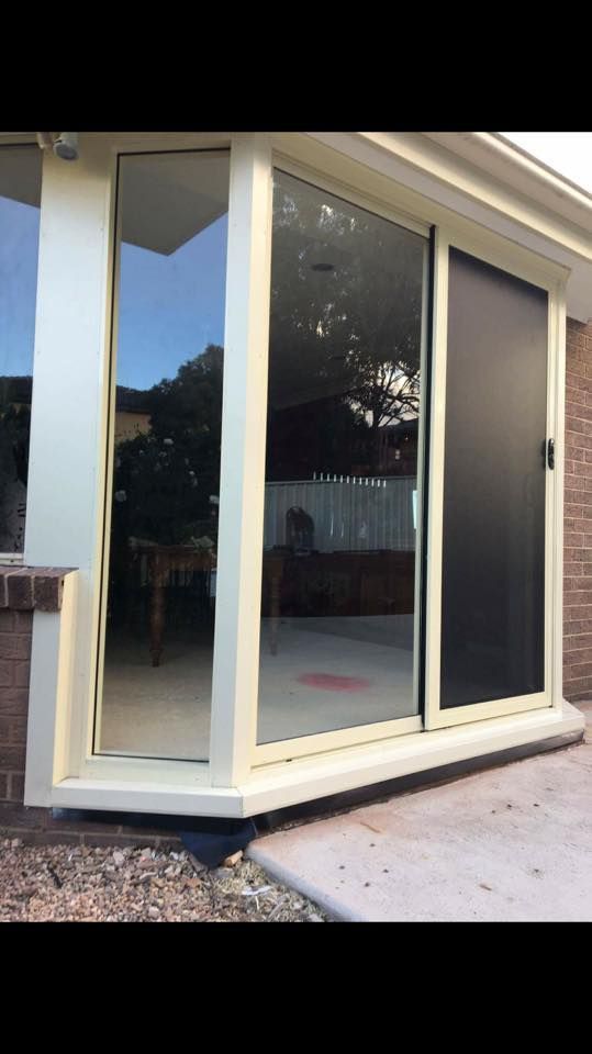 A Sliding Glass Door Is Sitting on The Side of A House — Distinctive Glass & Aluminium in Port Kembla, NSW