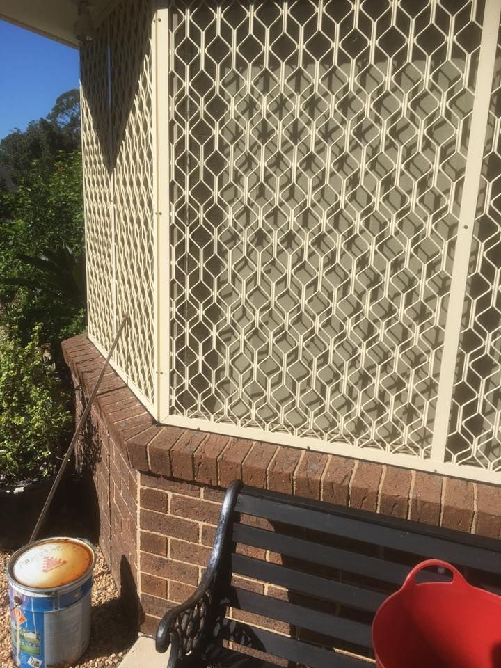 A Black Bench is Sitting in Front of a Brick Building Next to a Can of Paint — Distinctive Glass & Aluminium In Port Kembla, NSW