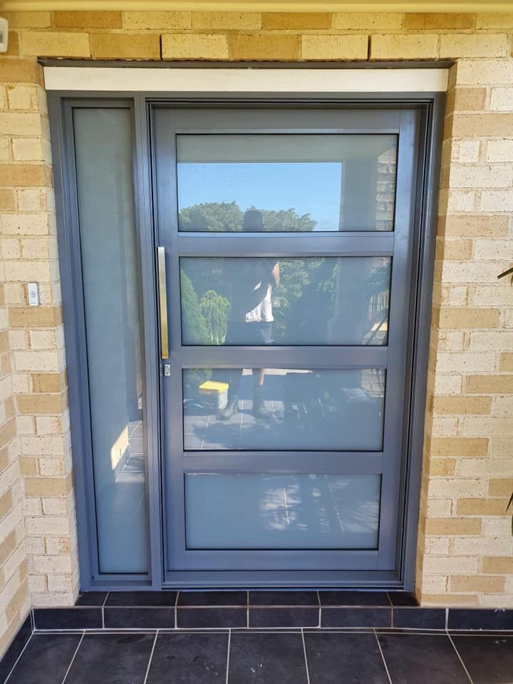 A Door with A Brick Wall Behind It — Distinctive Glass & Aluminium in Port Kembla, NSW
