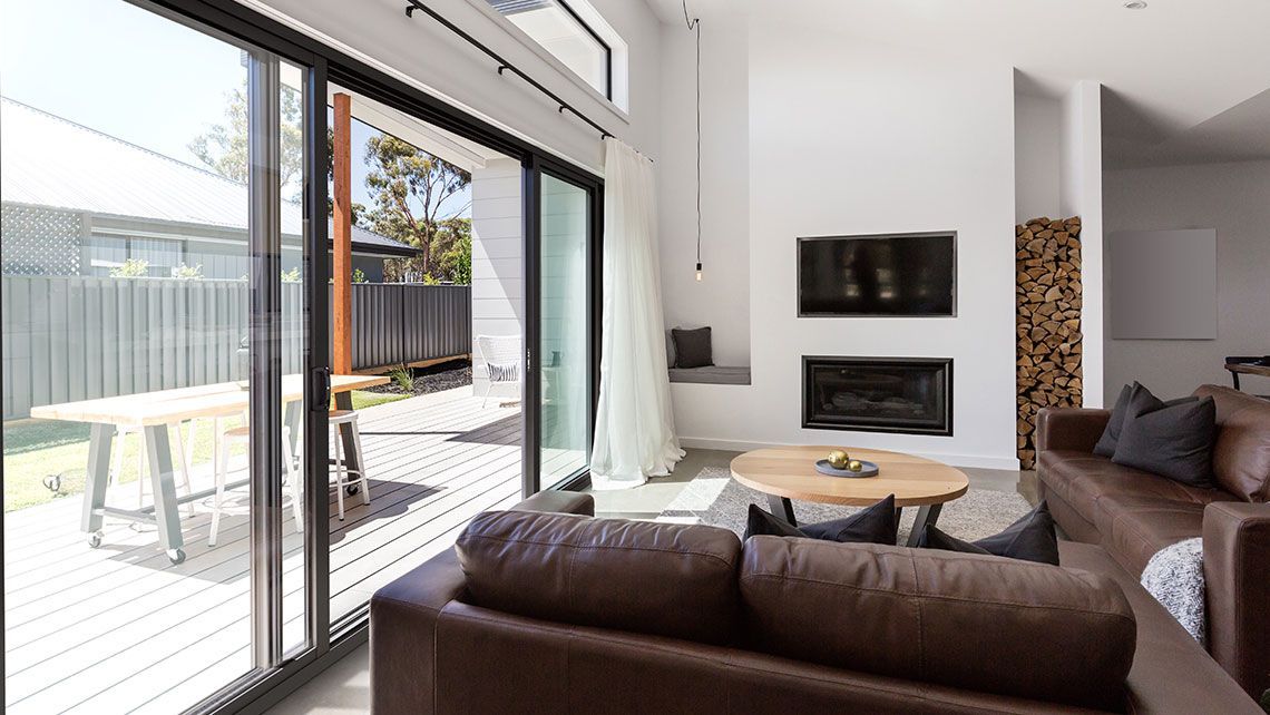 A Living Room with A Couch, Fireplace and Sliding Glass Doors — Distinctive Glass & Aluminium in Port Kembla, NSW