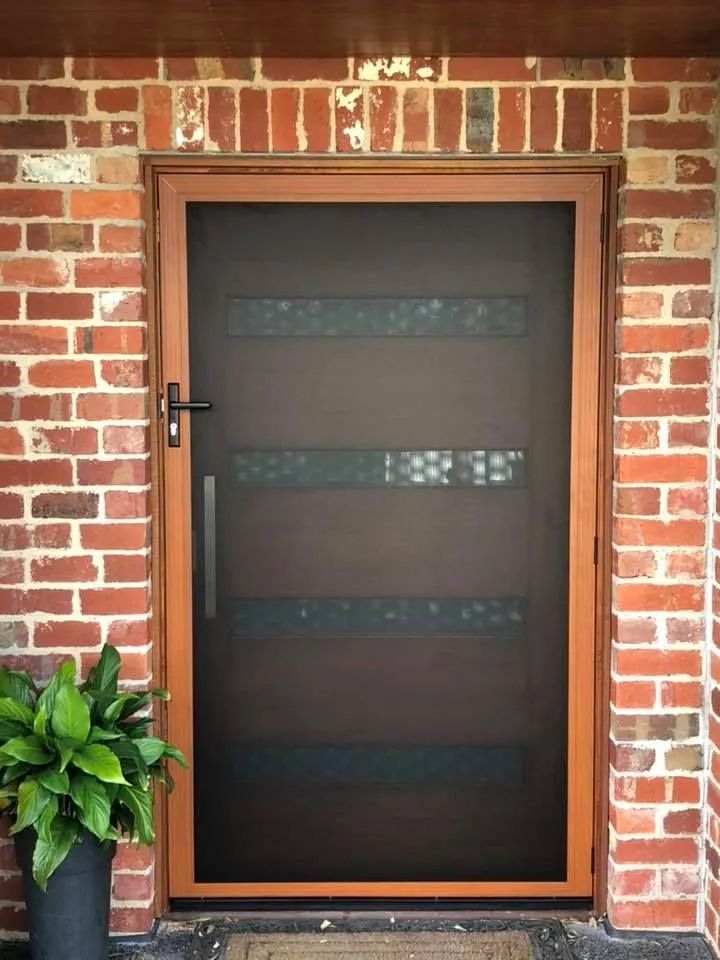 A Screen Door is Sitting on a Brick Wall Next to a Potted Plant — Distinctive Glass & Aluminium In Port Kembla, NSW