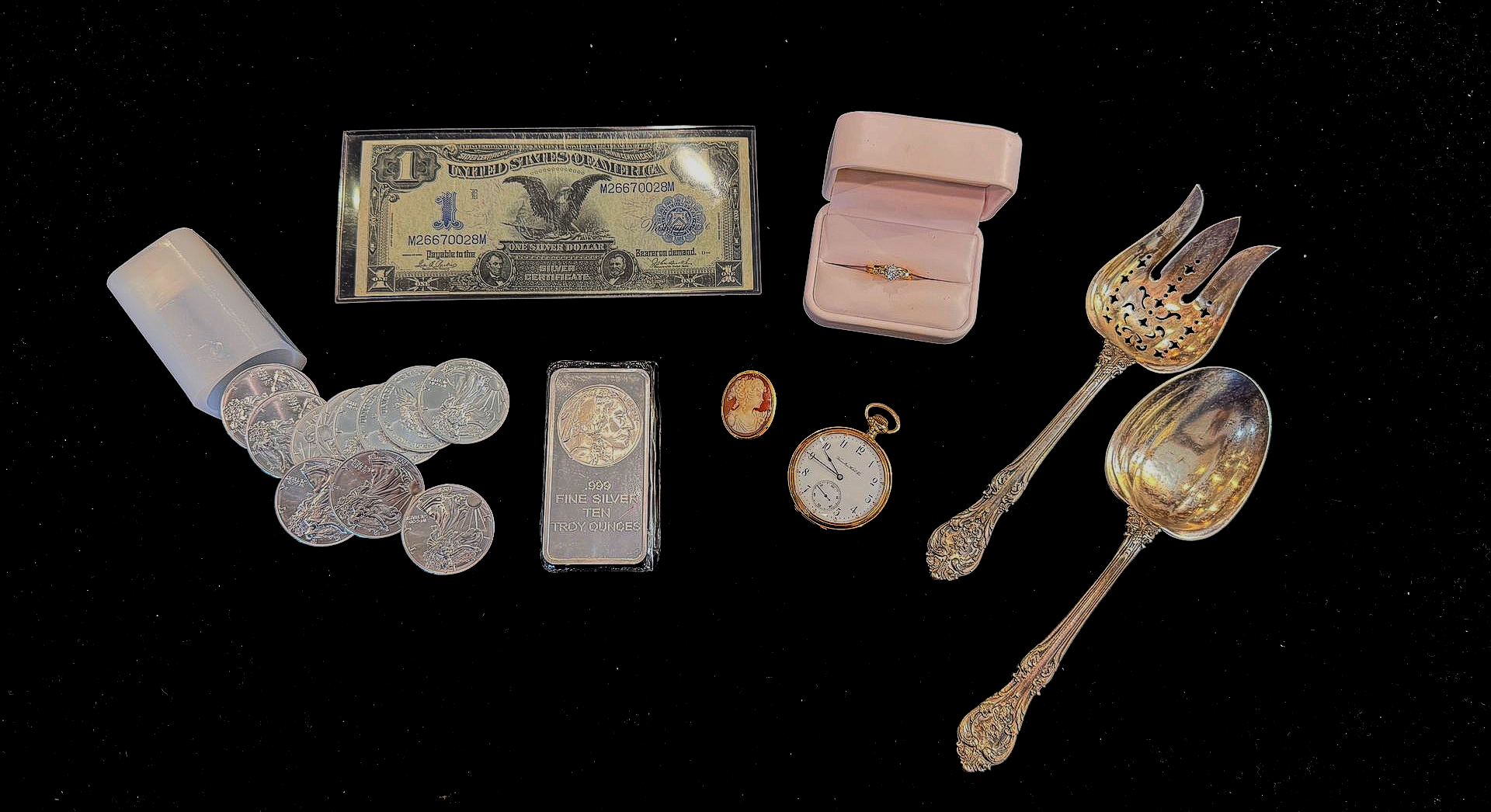 Assorted valuables on black background: rolled coins, dollar bill, jewelry box with ring, pocket watch, silverware.