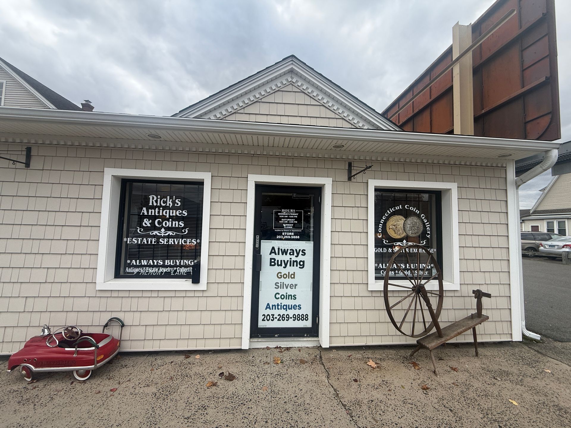 Rick's Antiques & Coins front facade with shop windows and a doorway; a vintage toy car is parked in front.