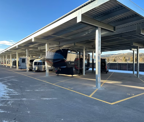 Boat and RVs parked in covered storage bays with marked asphalt drive
