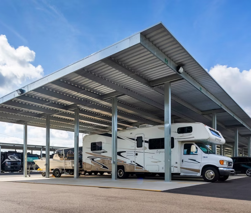 Motorhomes parked in paved, covered RV storage with steel canopy
