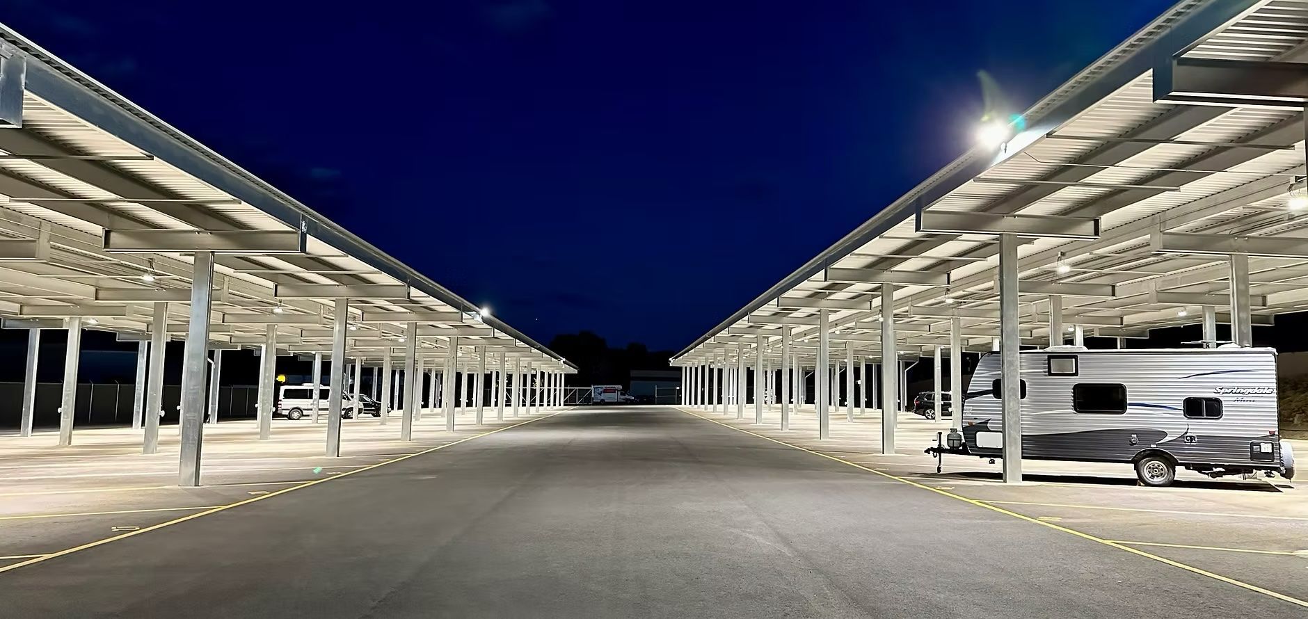 Well-lit RV storage facility at night with LED floodlights and covered parking