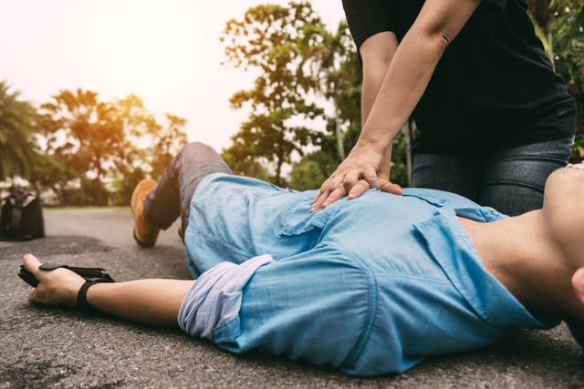 CPR chest compressions being performed on a person lying on the ground