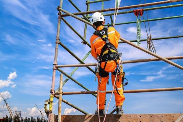 Worker in a safety harness climbing scaffolding