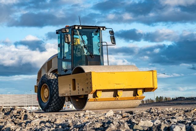 Smooth drum roller compacting gravel on a construction site