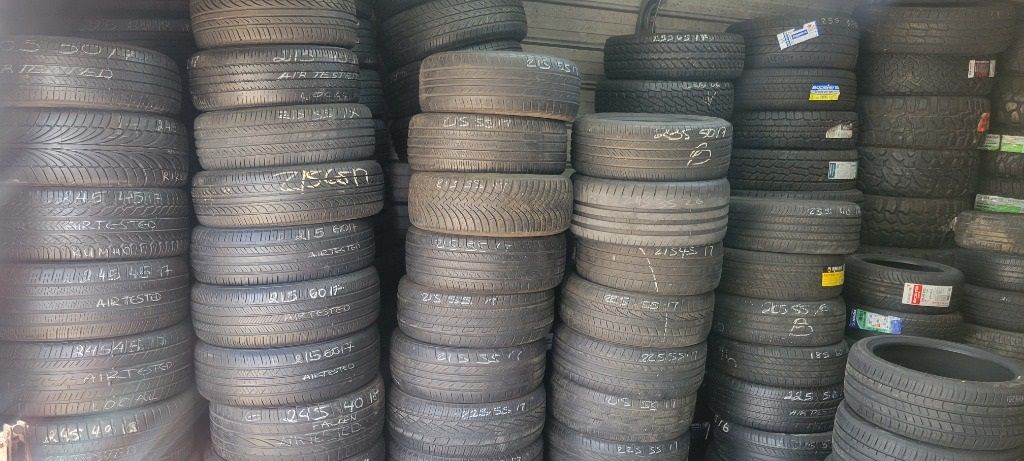 A bunch of tires are stacked on top of each other in a garage.