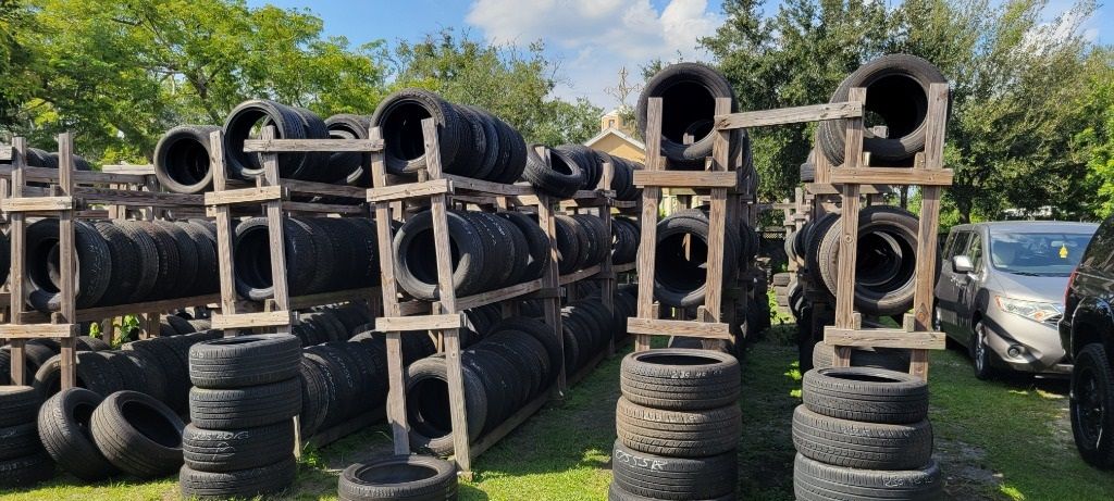 A bunch of tires are stacked on top of each other in a field.