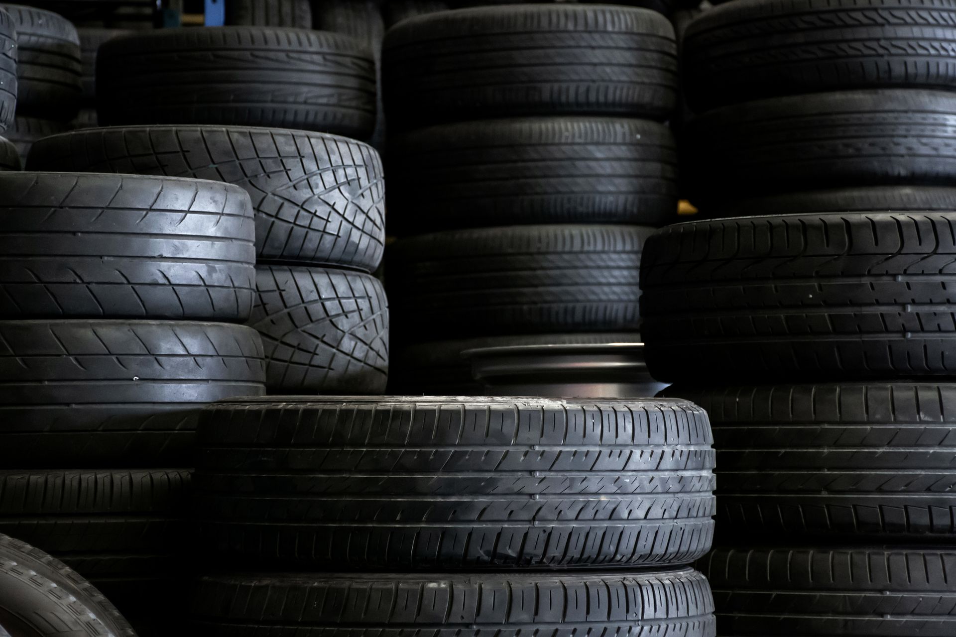 A bunch of tires are stacked on top of each other in a warehouse.
