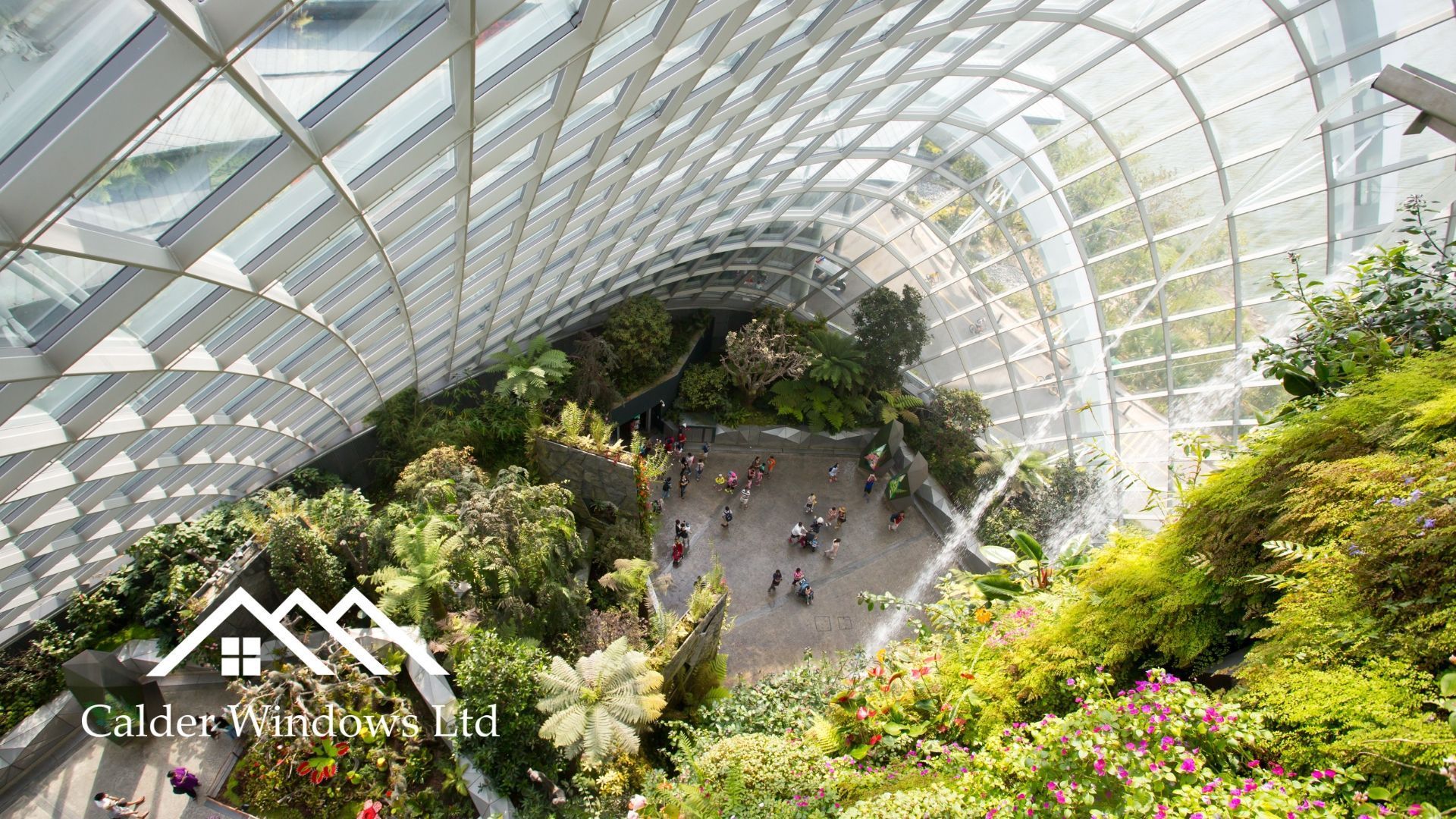 Glass-domed tropical garden with lush greenery and a few people walking below
