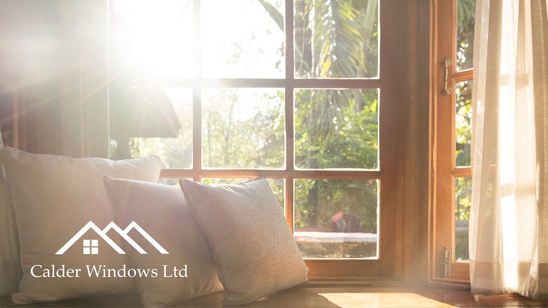 Sunlit window seat with pillows and a warm wooden frame, logo reading “Golden Windows Ltd.”