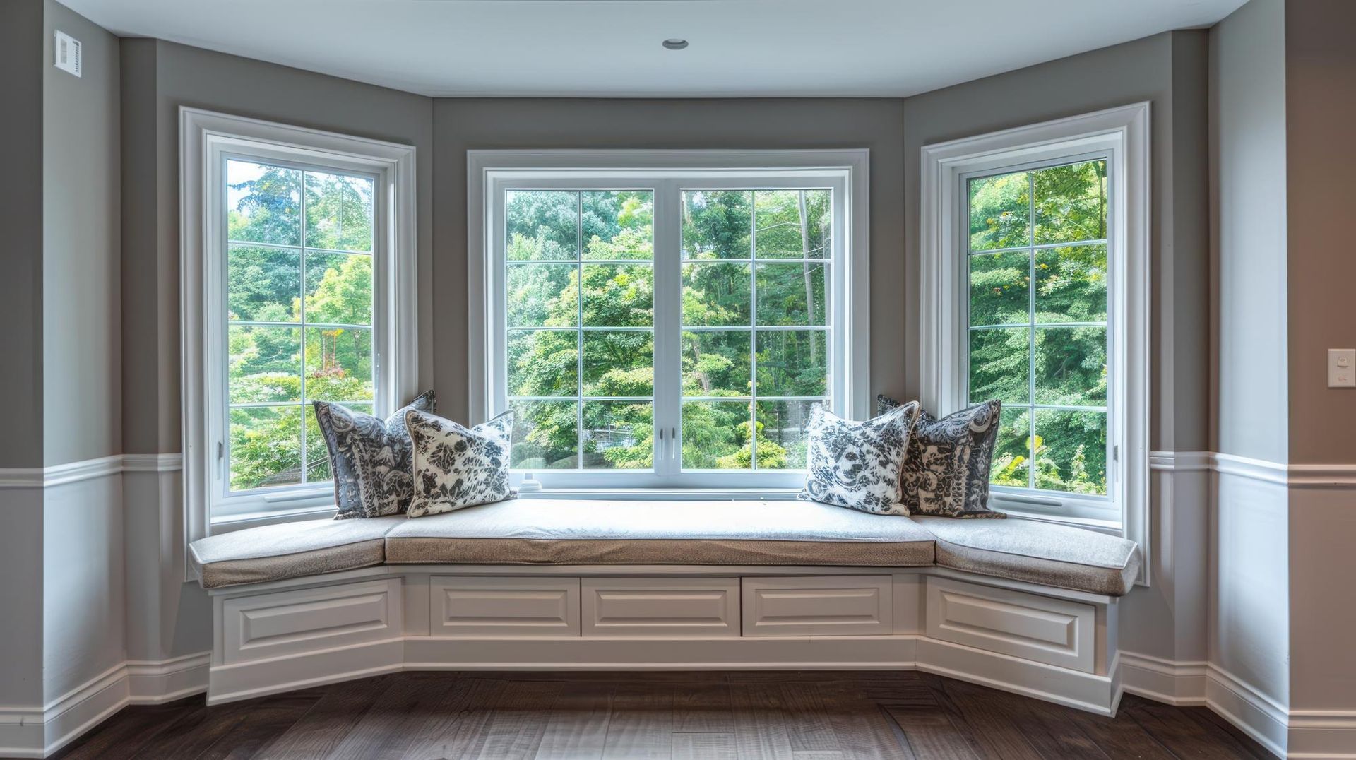 Curved window seat with cushions in a bright room overlooking green trees