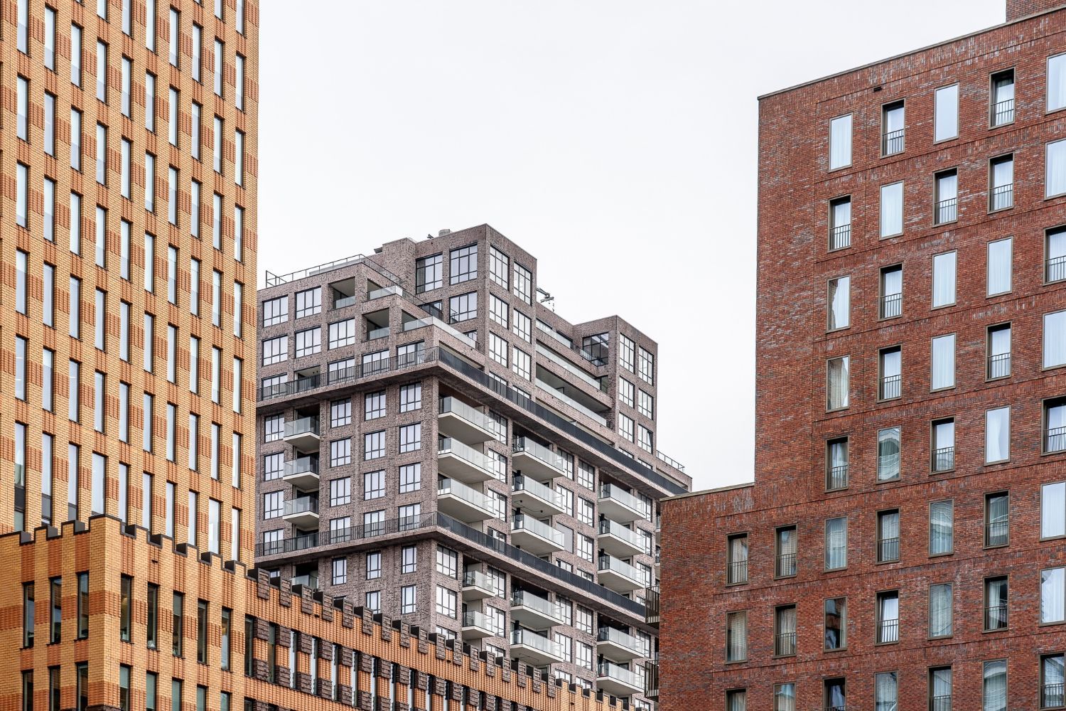 Modern apartment buildings with brick and glass facades against a cloudy sky