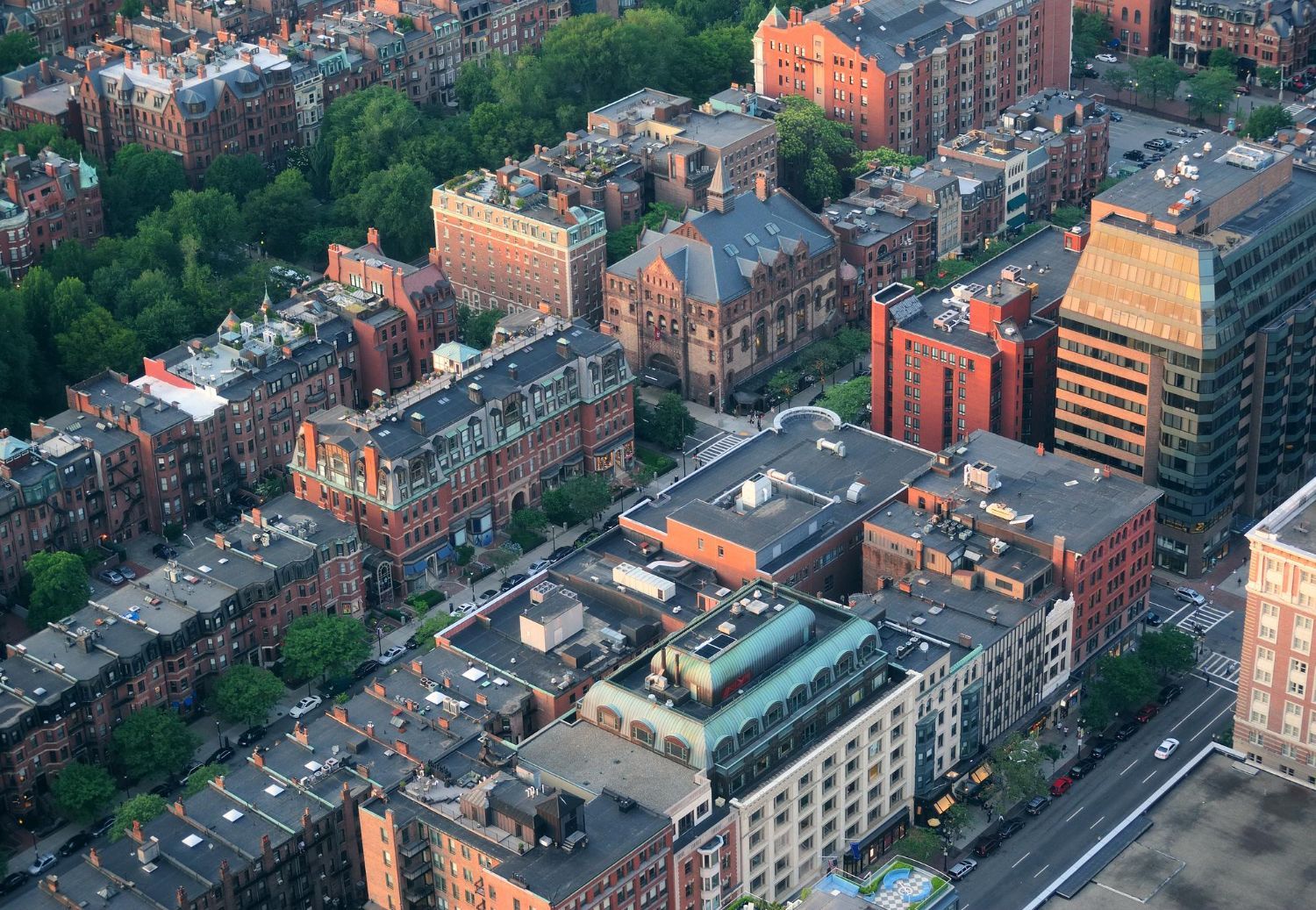 Aerial view of a dense city block with brick apartment buildings and tree-lined streets.