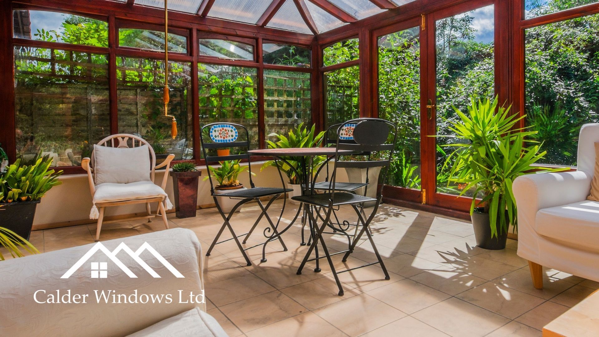Sunroom with wicker chairs, round table, potted plant, and large windows overlooking greenery