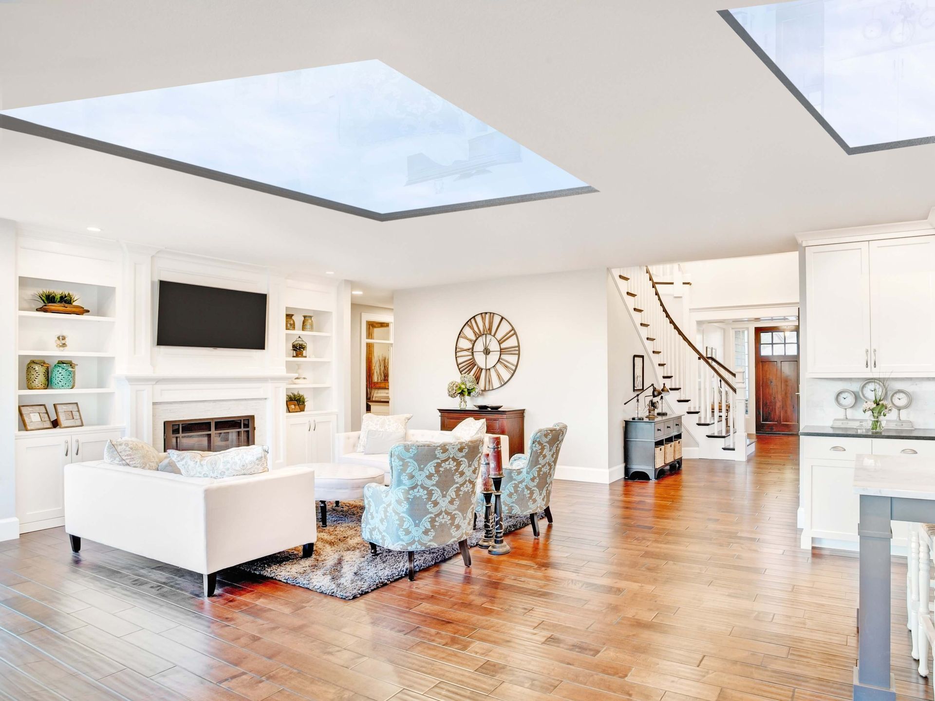Bright open living room with white sofa, fireplace, skylights, and hardwood floors