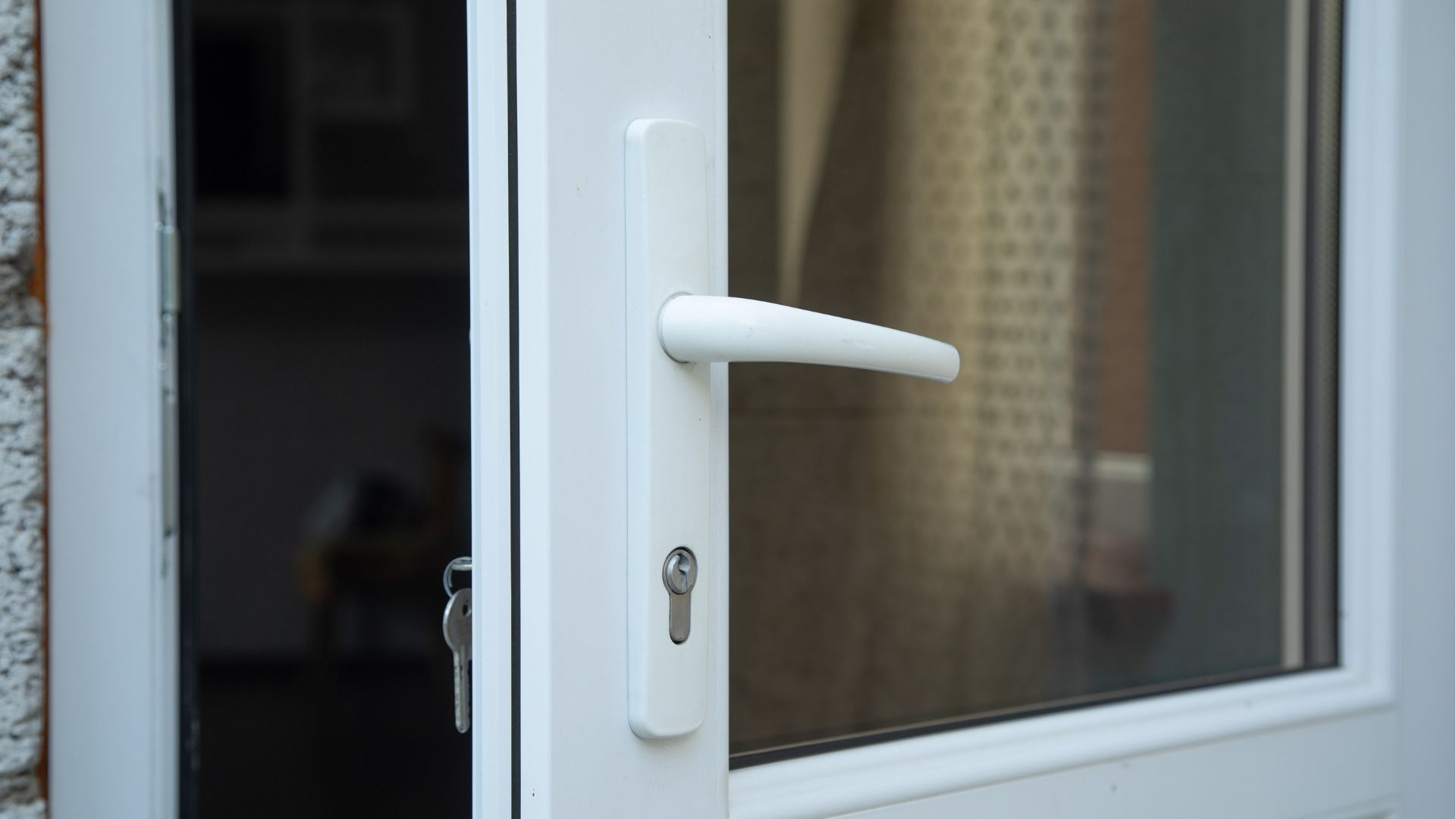 White door handle on a partially open white-framed glass door
