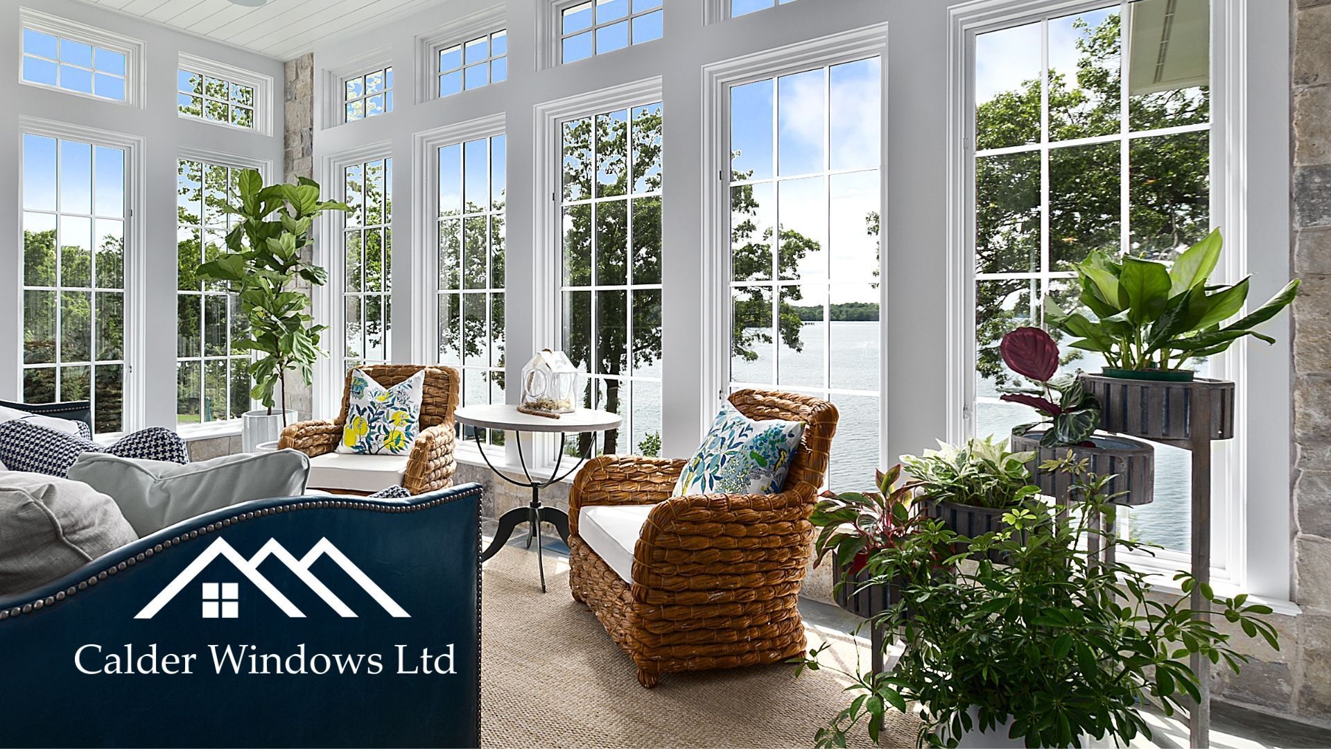 Bright sunroom with white windows, wicker chairs, and lush potted plants near a garden view.