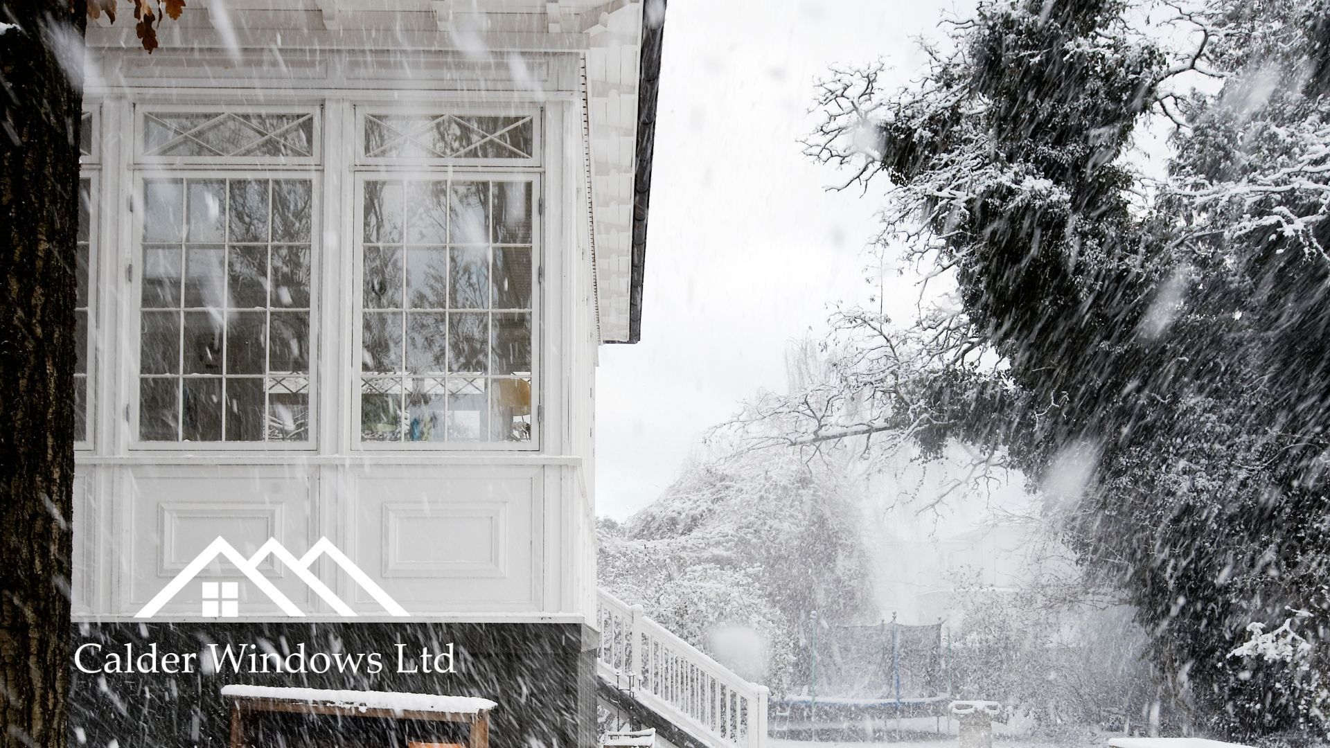 Snowy house exterior with white windows, porch, and trees covered in winter frost