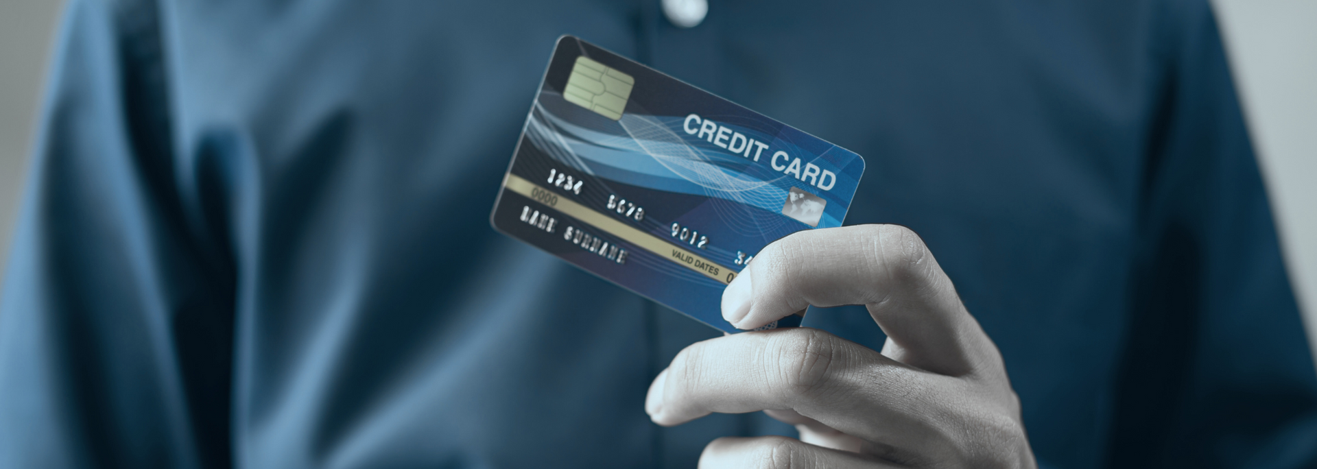 Gloved hand holding a blue credit card against a blurred blue background