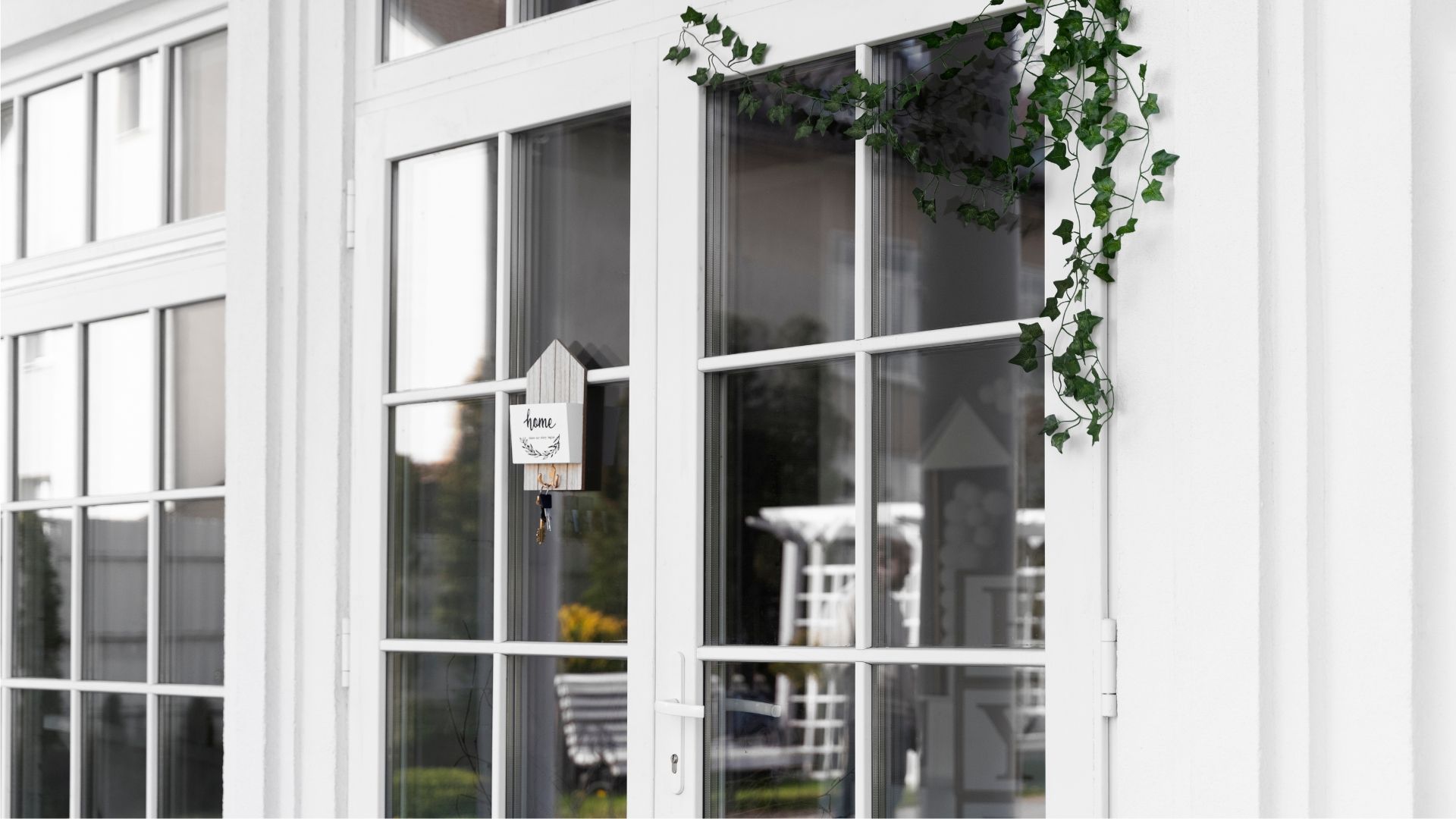 White storefront entrance with glass doors, window panes, and green ivy climbing the corner