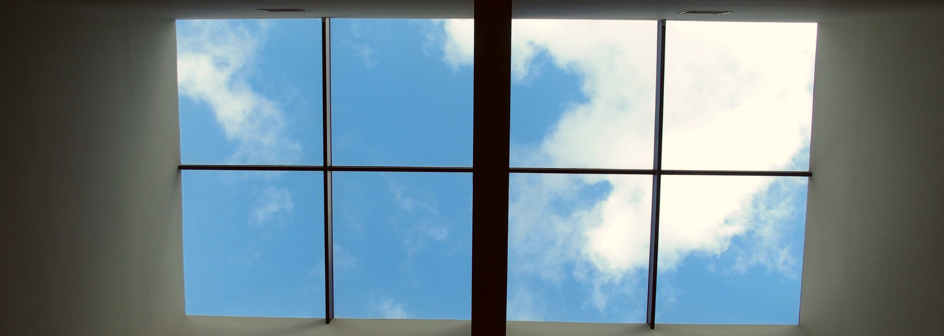 Window panes framing a bright blue sky with white clouds