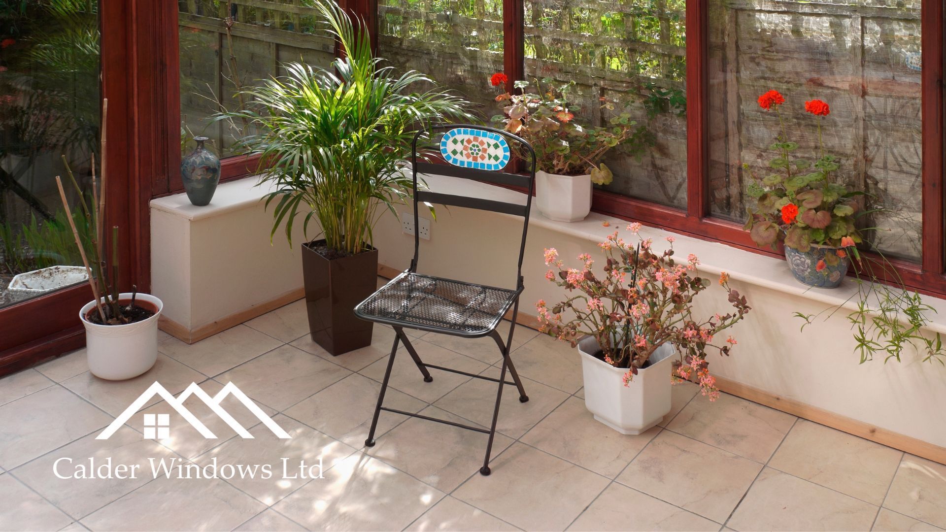Sunlit patio with potted plants, a folding chair, and a glass table by a screened wall