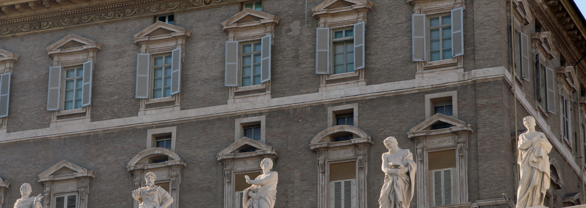 Stone building facade with ornate windows and small statues below the roofline