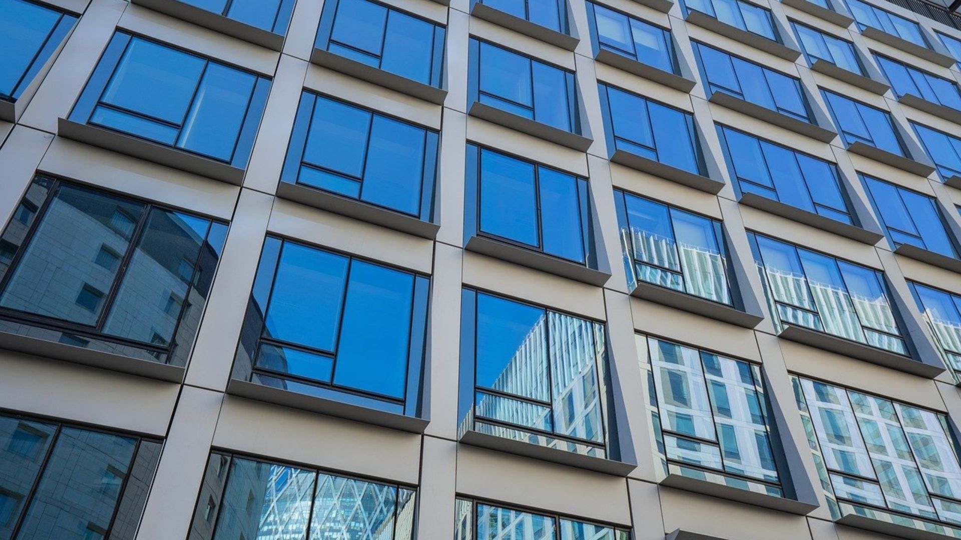 Modern glass-and-concrete apartment building facade with blue-tinted windows and balconies