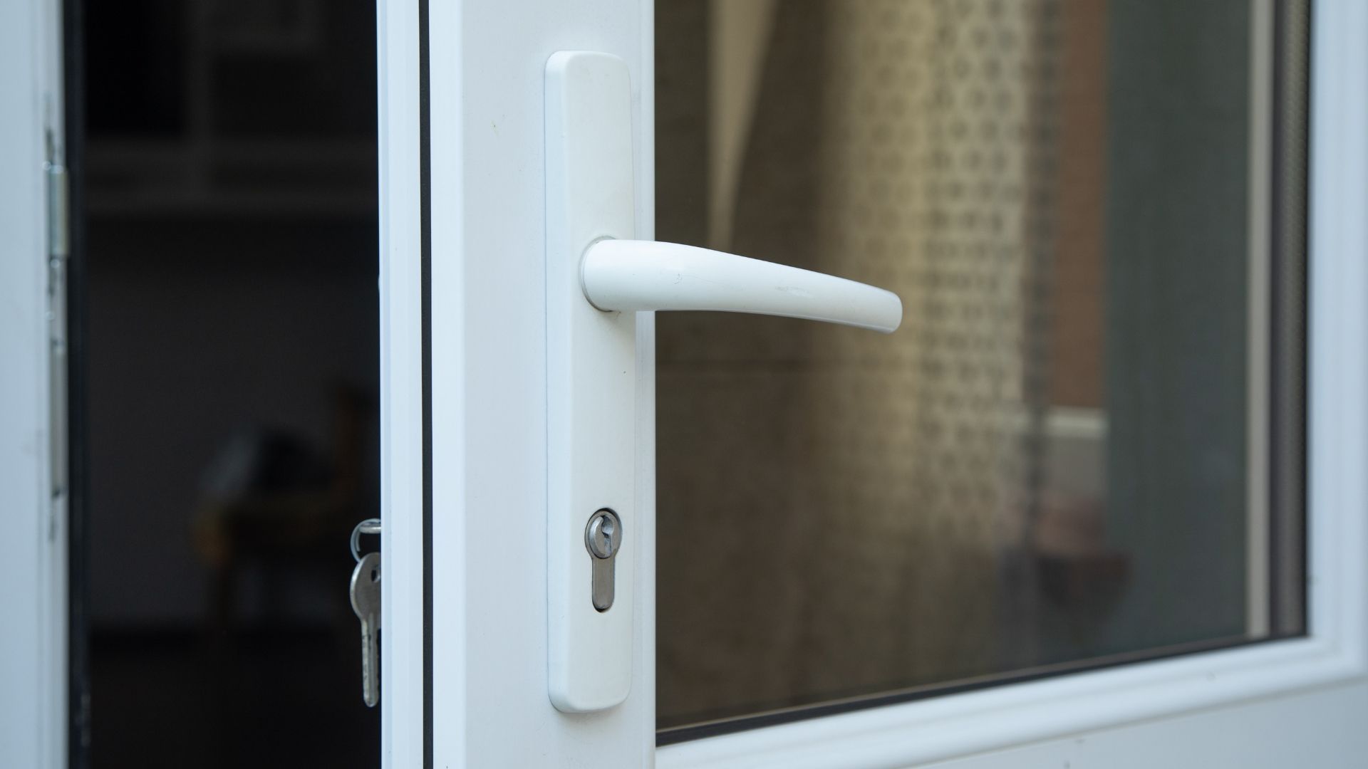 White door handle on a glass patio door, viewed close-up.