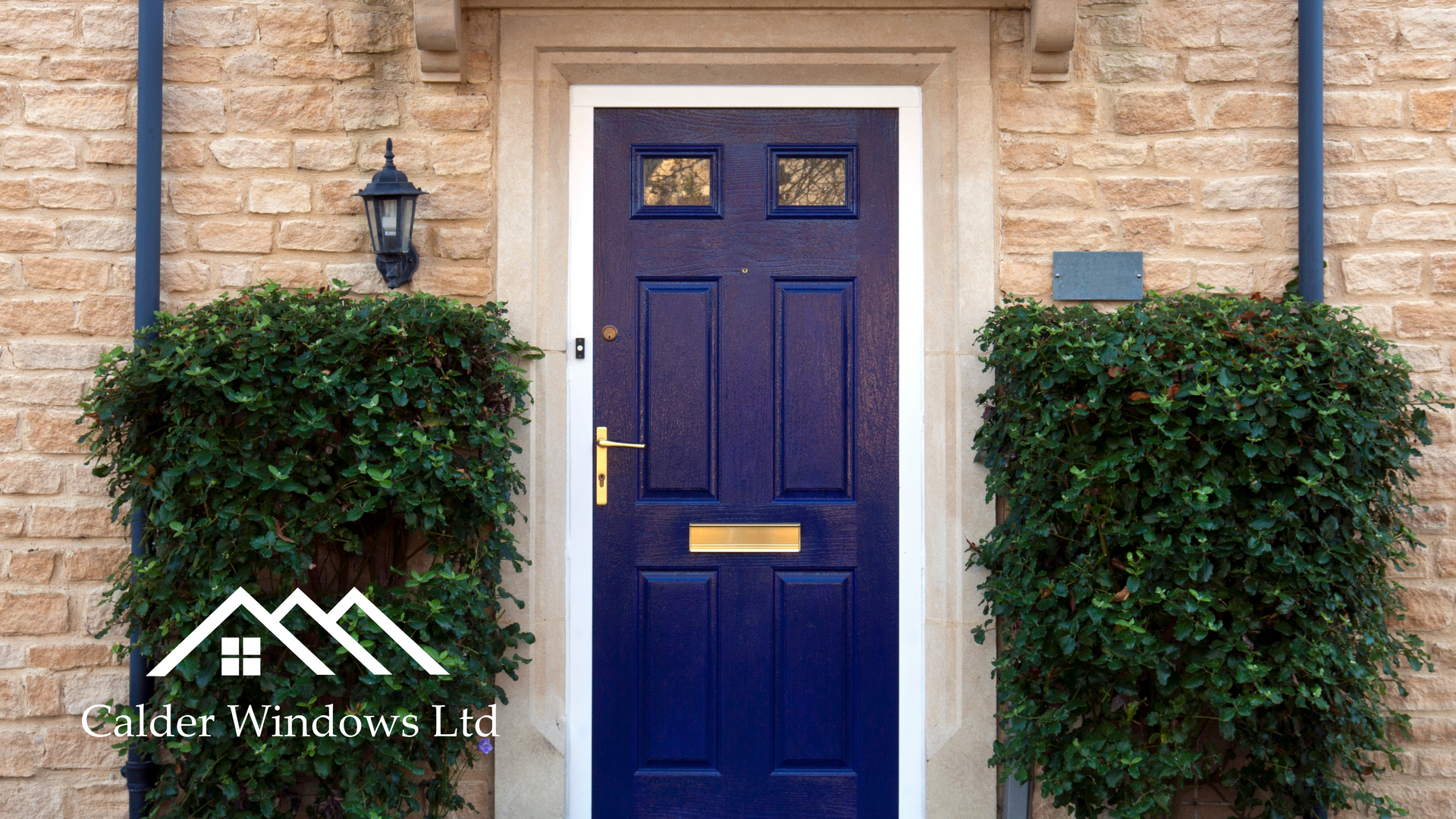 Blue front door framed by brick, with two trimmed green shrubs and wall lanterns