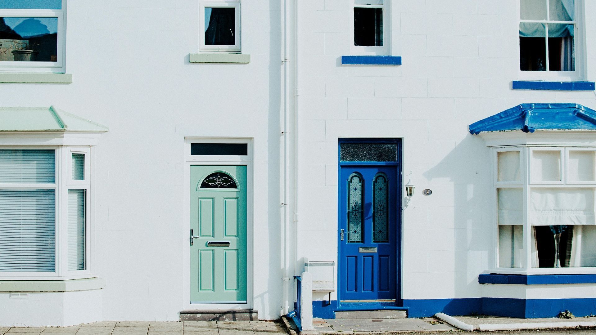 Row of white cottages with blue trim and doors along a quiet street