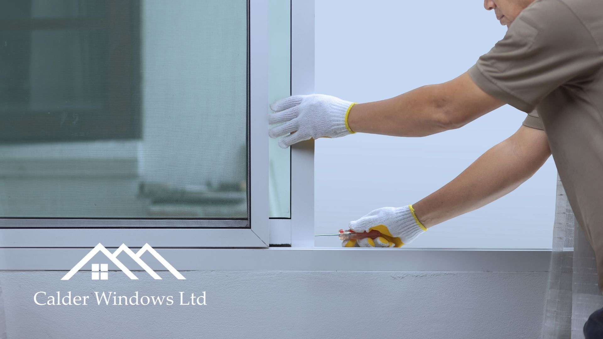 Worker cleaning a white window frame with a cloth and sponge beside a glass door