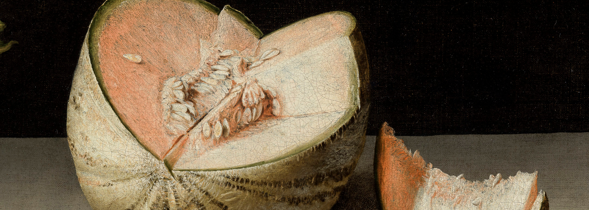 Torn open coconut with white flesh on a dark surface, with a broken shell piece nearby
