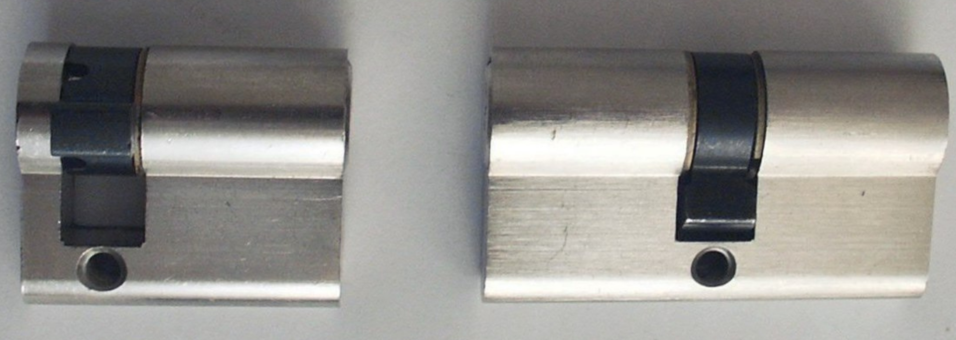 Two silver door locks with black accents mounted side by side on a white surface