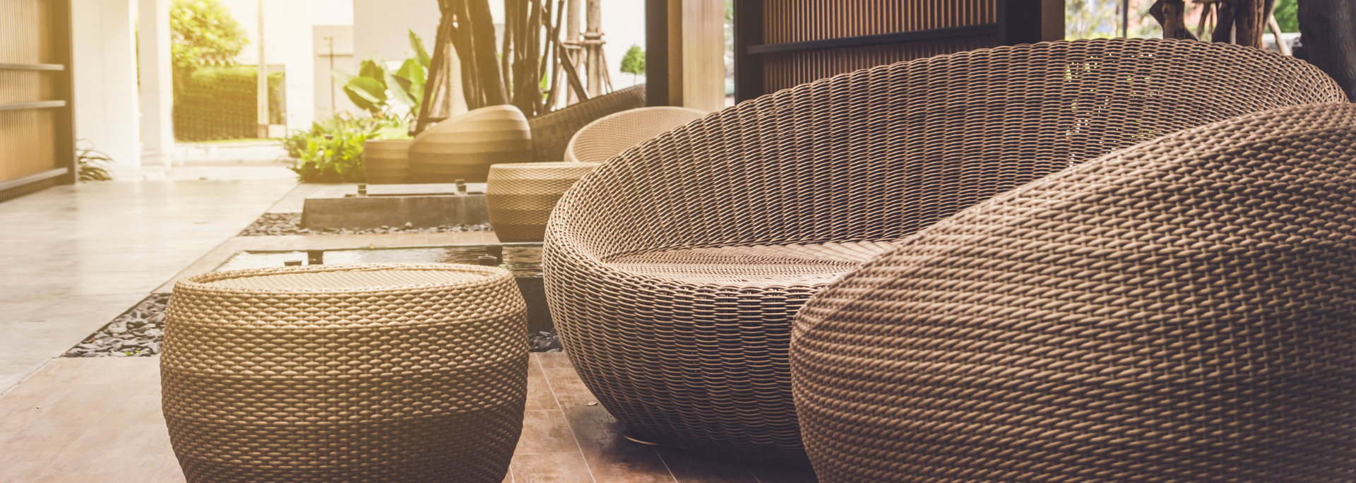 Sunlit patio with woven lounge chairs and ottomans by a window
