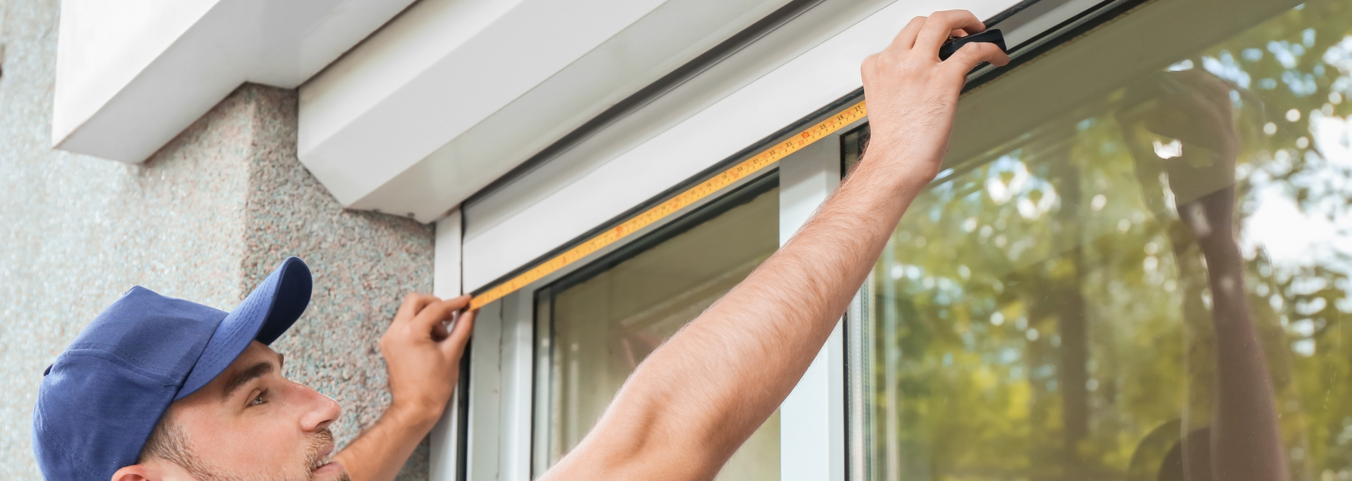 Worker measuring a window frame with a tape measure on a building exterior